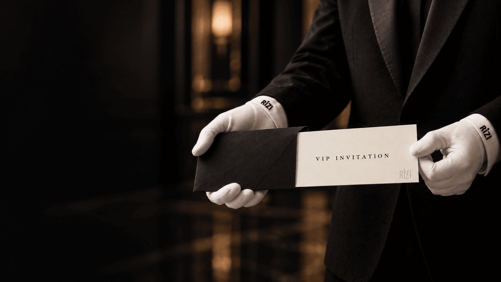 White-gloved hands presenting a Rizi invitation in a black envelope.